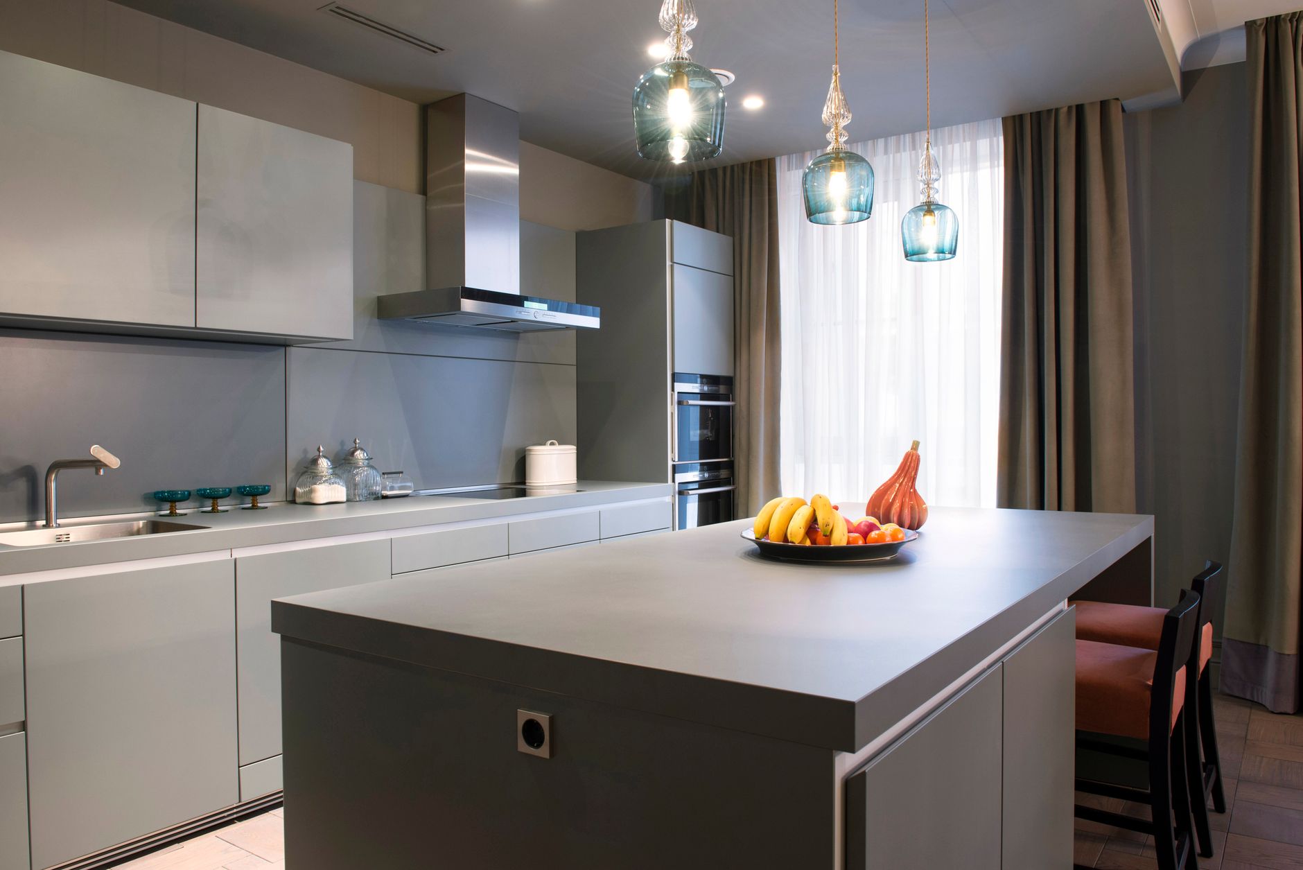 An open plan kitchen with a large island, pendant lights and a living area behind it