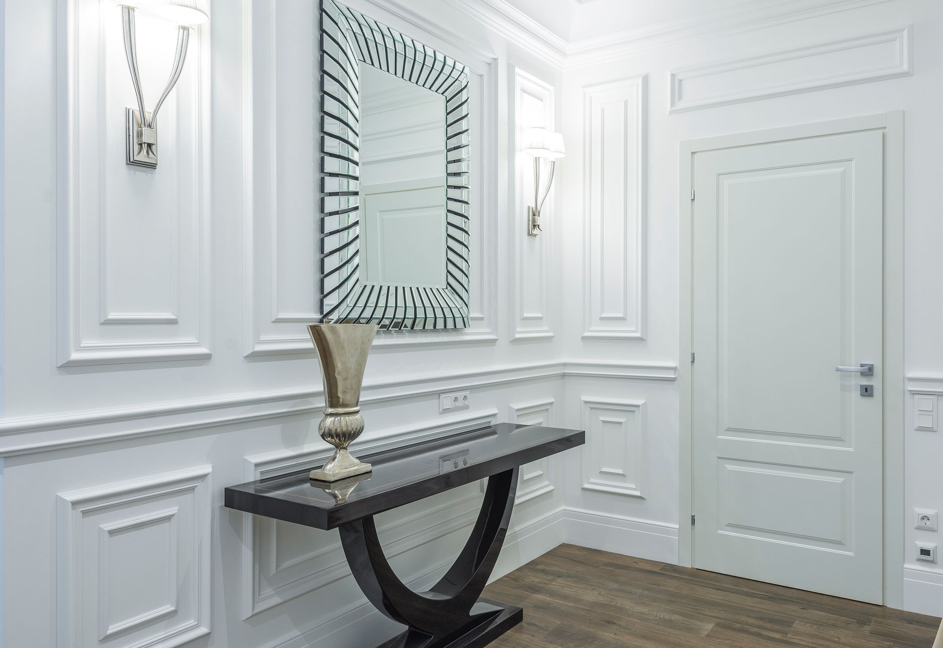 A hallway entry with a round mirror above a console table against a side wall