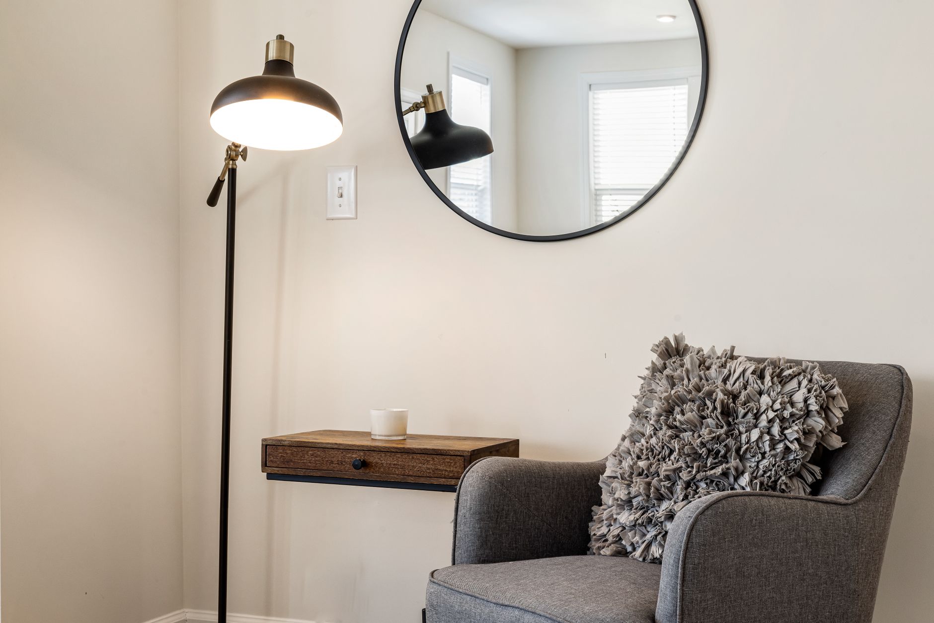 A small desk tucked into a corner of a living room next to a shelf