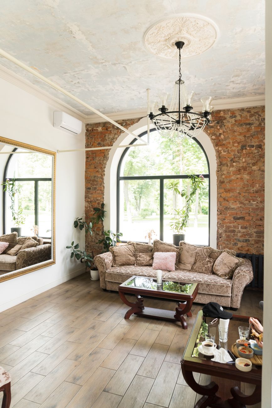 A large mirror on a wall reflecting a window and the daylight coming through it